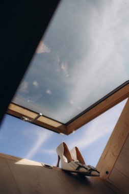 Wedding shoes on the window frame of the window in the ceiling clipart