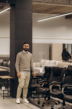 Bir adam mobilya dükkanında bilgisayar koltuğu seçiyor.