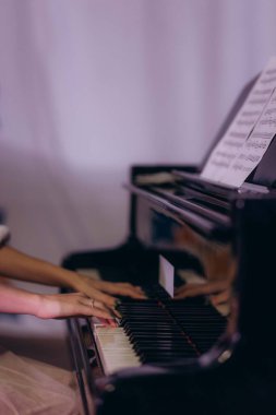 Eller zarif bir şekilde piyano çalıyor, müzik çalışmasında müzik notaları görünür bir şekilde yakalanıyor..