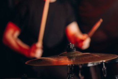 Bir davulcunun yakın plan görüntüsü konser sırasında enerjik bir şekilde müzik çalar, loş bir atmosferde titreşimler ve ritmik desenler yaratır..