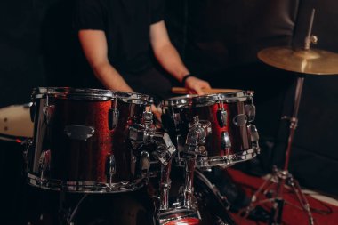 Canlı kırmızı davul seti loş stüdyo ışıkları altında müzik ve performansı vurgulayan bir müzisyen tarafından çalınıyor..