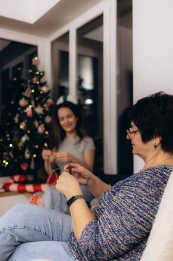 Güzel dekore edilmiş bir Noel ağacının yanında kuşakların örgü ördüğü, aşk ve gelenek anlarını paylaştığı yürek ısıtan bir sahne. Festival sezonunda aile birliğini ve yaratıcı eğlenceleri kutluyoruz..