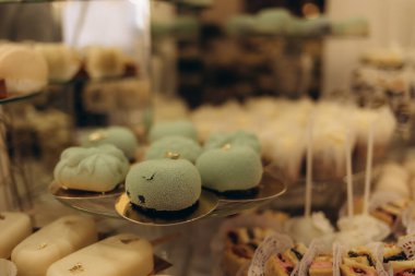 Eşsiz dokulara, pastel tonlara ve sanatsal tasarımlara sahip çeşitli lezzetlere sahip güzel bir tatlı sunumu, etkinlikler, partiler veya özel durumlar için çekici bir görsel deneyim yaratıyor..