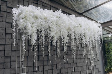 Asılan kristal elementlerle süslenmiş güzel beyaz çiçekler düğünler, yıldönümleri ya da lüks kutlamalar gibi özel durumlar için zarif ve sofistike bir olay süsü oluşturuyor..