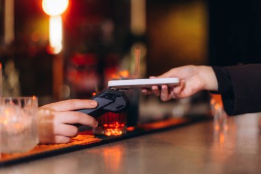 Şık bir restoran ortamında, dijital işletim kolaylığı ve modern teknoloji evlat edinmesini vurgulayan, irtibatsız bir ödeme için kullanılan bir akıllı telefon.