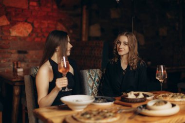 İki kadın rahat bir restoranda sıradan bir akşam yemeği yiyip sohbet ediyorlar. Görüntü, sıcak ve dost canlısı bir atmosferi enfes yemekler ve arkadaşlık duygusuyla yakalıyor..
