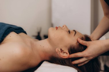Profesyonel bir spa tedavisi sırasında kafa masajından zevk alan birinin rahatlatıcı bir tasviri. Rahatlamanın, stres atmanın ve rahatlatıcı bir ortamda kendine bakmanın özünü yakalar..