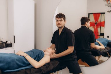 Huzurlu bir stüdyoda müşteriye kafa masajı yapan bir sağlık terapisti. Çevre, bütünsel bakım isteyen müşterilere lüks bir deneyim sunarak rahatlama ve refahı teşvik eder..