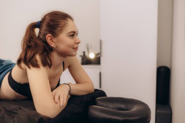 Masaj masasında dinlenen, rahatlama ve sükunet sağlayan genç bir kadının huzurlu bir görüntüsü. Sağlık, kişisel bakım ve terapi kavramları için mükemmel..