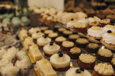 Kademe stantlarda zarif bir şekilde sunulan çeşitli pasta ve tatlı koleksiyonu, kutlama için ideal, karmaşık tasarımlar ve gurme kalitesi sergileniyor..