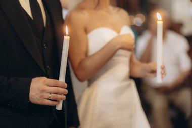 Gelin ve damat kutsal bir düğün töreninde mum yakar. Kilisedeki kutsal anı izleyen katılımcılar birlik ve sevgiyi simgeler..