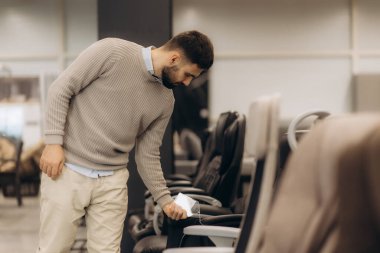 Genç bir adam kamuya açık bir ortamda ofis sandalyesini temizlemek için hijyen ve temizliğe dikkat çekmek için dezenfekte spreyi kullanıyor. Parlak uzay düzen, profesyonellik ve güvenliğe dikkat eder..