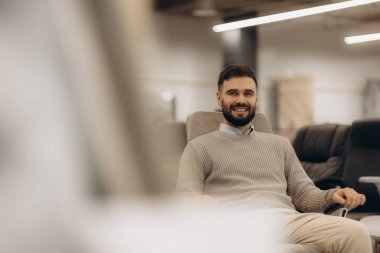 İçerde rahat bir sandalyenin keyfini çıkaran neşeli bir adam, hoş bir karşılama ve rahat bir atmosfer sergiliyor..