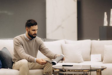 Şık bir kanepede oturmuş dergilere bakan bir adam. Modern ve son model iç tasarım..