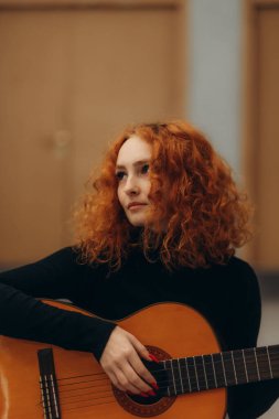 Akustik gitar tıngırdatan kızıl saçlı kadın içeride yaratıcı ve rahatlatıcı bir an yakalıyor..