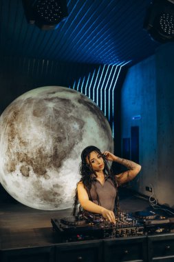 Sahnede müzik çalarken müzik yapan bir DJ, büyük bir ışıklandırma ve dinamik bir stüdyo ışıklandırması, ilahi ve enerjik bir performans ortamı yaratıyor..