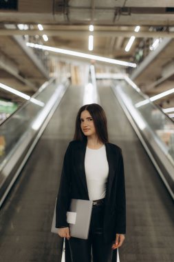 Kendine güveni tam profesyonel bir kadın merdivenlerin yanında şık giyinmiş modern bir şehir ortamında zarafet ve kararlılık sergiliyor..