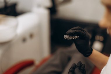 Eldivenli bir profesyonel klinikte diş bakımı ve hijyeni vurgulayarak diş teli kullanır..