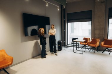 Çağdaş mobilyalar ve geniş doğal ışık ile çevrili, işbirliğini ve üretkenliği teşvik eden düşünceli sohbetler yapan iki meslektaşın yer aldığı modern bir ofis..