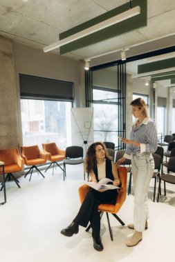 İki meslektaş, modern bir ofiste, takım çalışması ve iletişimi profesyonel bir ortamda vurgulayarak verimli bir tartışmaya giriştiler. Mekan iyi dekore edilmiş, yaratıcılık ve odaklanma çağrıştırıyor..