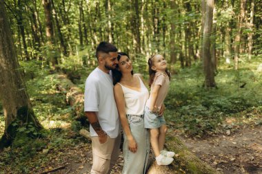 Neşeli bir aile, doğanın huzuru içinde, ormanın güzelliğini kucaklayan ve birbirlerinin arkadaşlığını paylaşan keyifli bir anı paylaşır..