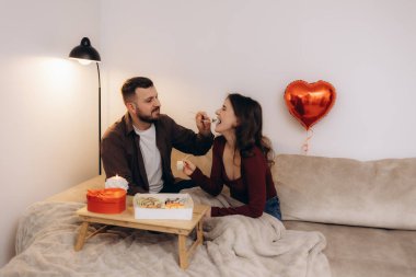 Sevgi dolu bir çift romantik bir akşam geçirir, kanepede suşi yer, kalp şeklinde kırmızı bir balonla, sahneye biraz cazibe ve sıcaklık katar..