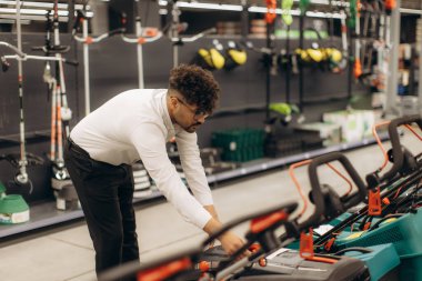 Mağazadaki bir çalışan, perakende sektöründe detaylara ve profesyonelliğe titizlikle dikkat eden ürünleri sergiliyor. Ekipman ve çevre, araçlar ve müşteri hizmetlerine adanmış bir işyerinin altını çizmektedir.