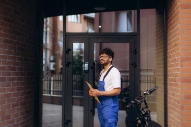 Gülümseyen teslimatçı elinde paketle binadan ayrılıyor.