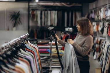 Genç bir bayan müşteri tarafından renkli kıyafetlerin satıldığı modern giyim mağazası..