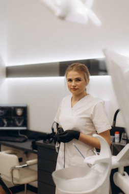 Şık bir klinik ortamında kendine güvenen bir diş hekimi profesyonelliği ve bakımı yansıtıyor. Tıbbi, sağlık ve hijyen kavramlarına uygundur..