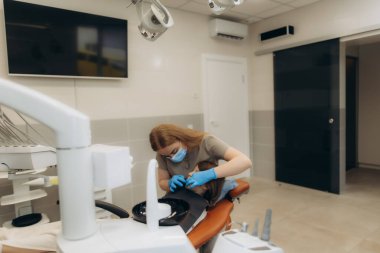 İyi donanımlı bir diş muayenehanesinde hastanın dişlerini hassas diş aletleriyle inceleyen dişçi, en iyi ağız hijyenini garanti altına alıyor.