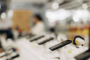 Bulanık bir elektronik mağaza arka planına sahip cep telefonu perakende elektronik alışverişi sergiliyor..