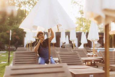 Havuz kenarında güneş şemsiyesi monte eden bakım işçisi, tatil köyünü önümüzdeki yaz için hazırlıyor.