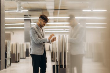 Profesyonel bir gözlemci, modern bir iç mekanda seçime odaklanarak, kapalı bir galeride malzeme örneklerini inceler..