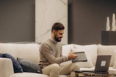 Neşeli bir birey elinde bir defter tutuyor ve bir dizüstü bilgisayarla görüntülü bir görüşme yapıyor. Bu da uzak bir ortamda verimlilik ve bağlantı olduğunu gösteriyor..