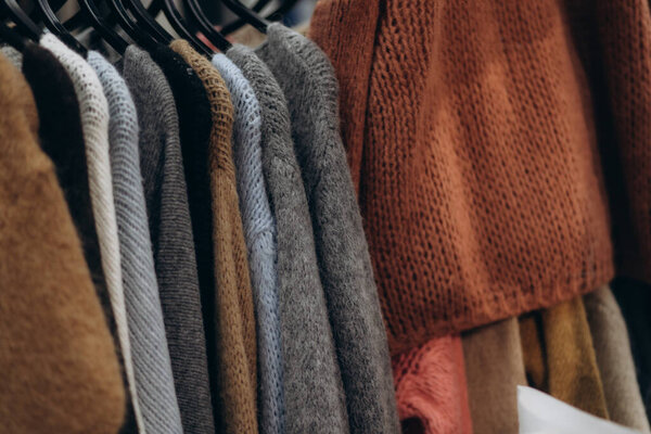 A collection of cozy knit sweaters in different colors displayed on hangers for fashion sourcing.