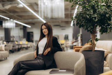 Modern bir iç dekorla modern bir iç mekanda oturan modern giyimli kadın kendine güveni, tarzı ve çağdaş yaşam tarzını simgeliyor..