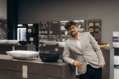 Modern ev eşyaları ve aletleri sergi salonunda duran profesyonel giyimli bir birey..