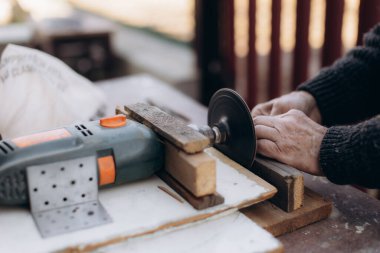Eller ahşap bir parça üzerinde çalışıyor. Tezgahtaki öğütme aletini kullanarak. Marangozluk, marangozluk becerileri ve geleneksel tekniklerin ön planda tutulduğu doğal ışıklandırma ortamı..