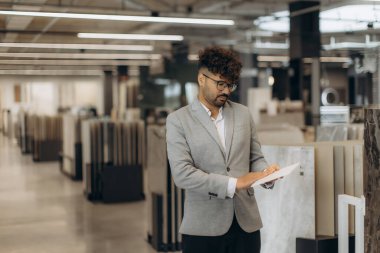Bir profesyonel, çağdaş bir sergi salonunda dolap malzemelerini inceler. Mimarlık, inşaat ve tasarım temaları için ideal.
