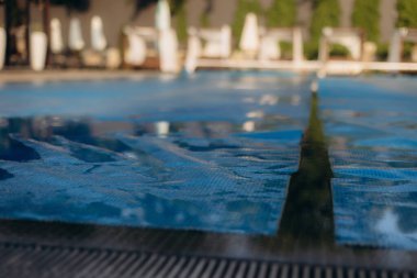 Yüzme havuzunu koruyan mavi bir havuz örtüsünün yakın plan görüntüsü, yaz kapanışı sırasında güvenlik ve su korunmasını sağlıyor.