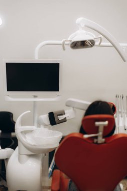 Modern sağlık hizmetleri ve dişçilik uygulamalarını temiz ve çağdaş bir ortamda tasvir eden, gelişmiş diş hekimliği ekipmanları ve tedavi bekleyen bir hastanın sergilendiği profesyonel bir diş sağlığı kliniği..