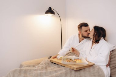 Romantik bir çift, sıcak ve rahat bir ortamda suşi yerken sevgi, rahatlama ve samimiyet duyguları yayıyor. Aşk, yaşam tarzı ve rahatlama kavramları için mükemmel..