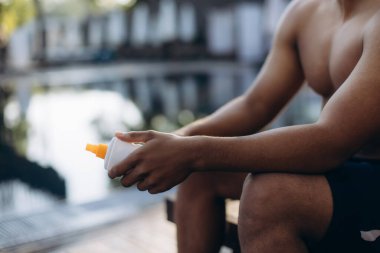 Yüzücü, havuza girmeden önce güneş kremi ve cilt bakımını öncelikli olarak uygulayarak eğitimine hazırlanıyor.