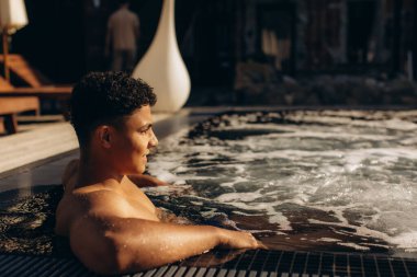 Genç bir adam lüks bir tatil köyünde, dinlendirici bir havanın keyfini çıkarıyor.