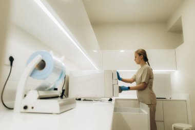 Steril eldiven giyen hemşire modern klinikte ya da hastane ameliyathanesinde sterilizatör kullanıyor.