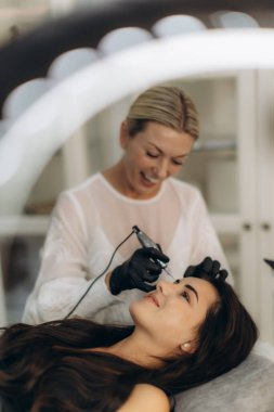 Profesyonel güzellik uzmanı. Güzellik salonundaki genç bir kadının kaşlarına mikropatinaj olarak da bilinir.