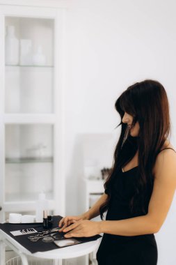 Modern bir güzellik salonundaki siyah tepside mikropatinaj işlemi için profesyonel aletler düzenleyen kadın güzellik uzmanı.