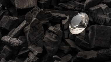 Siyah kömür zemininin ortasında pırlanta parlıyor. Değerli taşların c yapısı için kopyalama alanı konsepti, madende bulunan cilalanmış mücevher ve kristalize ve biçimsiz karbon allotroplar.