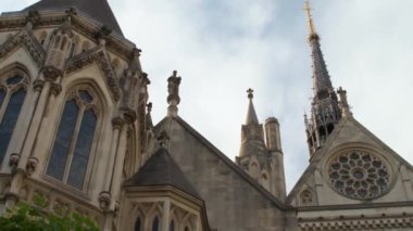 İngiltere 'nin başkenti Londra' da, gökyüzünden ve gotik kuleden, tarihsel arma odaklı Kraliyet Adalet Divanı girişine eğilen günışığı pansiyon videosu (amblem))